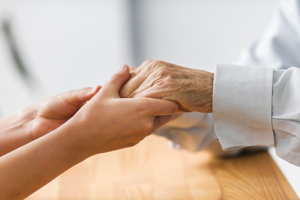 nurse holding senior man s hands for comfort